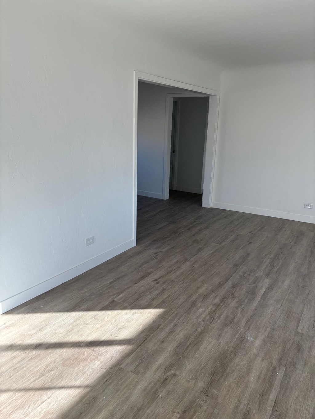 an empty living room with wood flooring and white walls