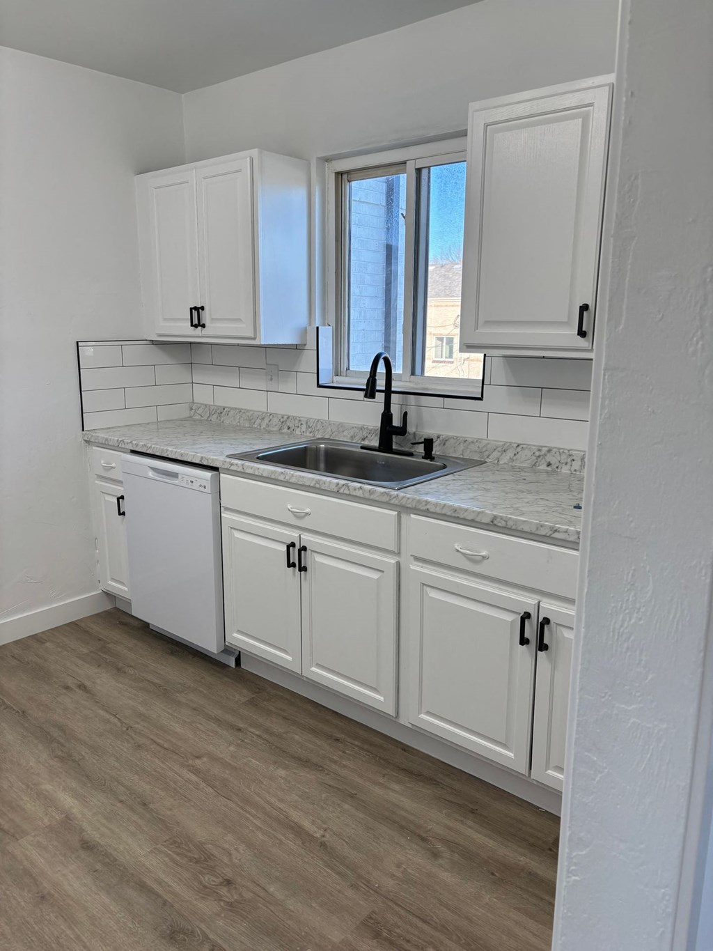 a kitchen with white cabinets and a sink and a window