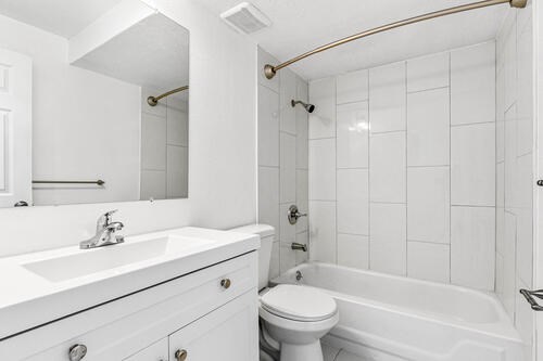A white bathroom with a toilet, sink, and bathtub.