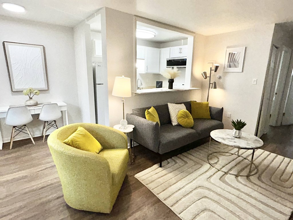 A living room with a yellow chair and a grey couch.