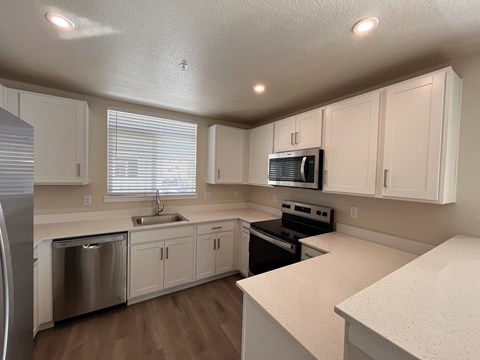A kitchen with white cabinets and a stainless steel dishwasher.