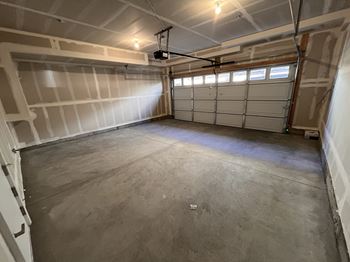 A spacious garage with a concrete floor and a white garage door.