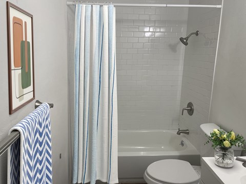 A white toilet sits next to a white bathtub in a bathroom.