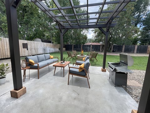 A patio with a table and chairs under a pergola.