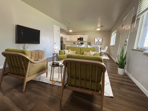 A living room with two green chairs facing a television.