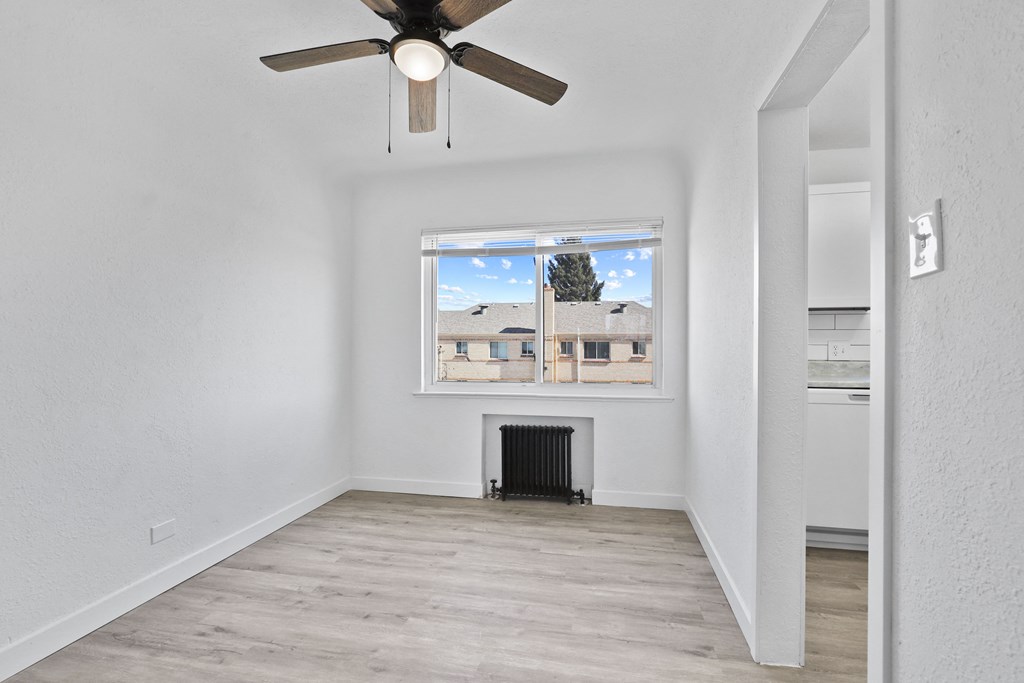 an empty living room with a ceiling fan and a window