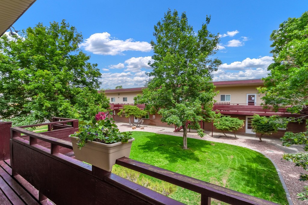 A view from a balcony overlooking a green lawn and apartment buildings.
