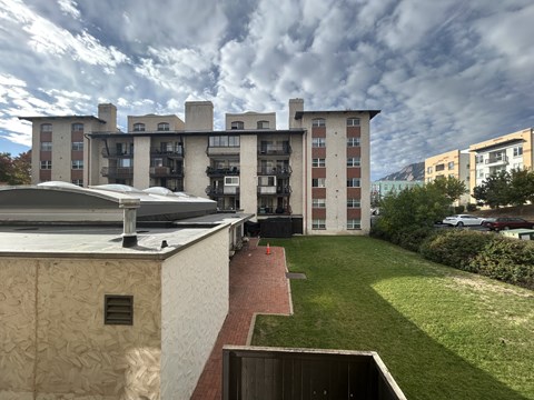 A modern building with a flat roof and a green lawn in front.
