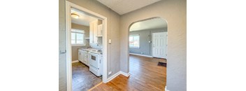 A kitchen with white appliances and wooden floors.