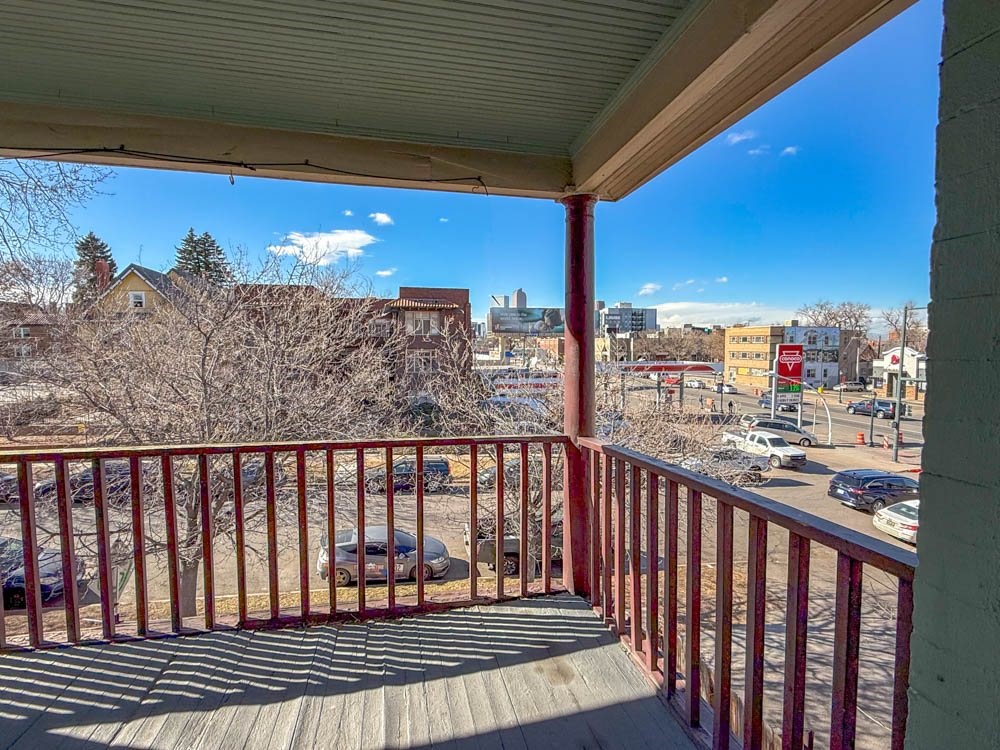 A view from a balcony overlooking a parking lot and buildings.