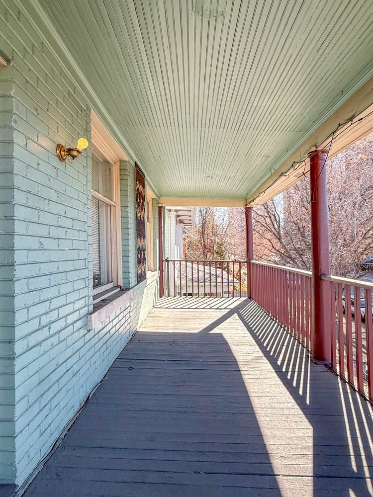 A porch with a red railing and a white wall.