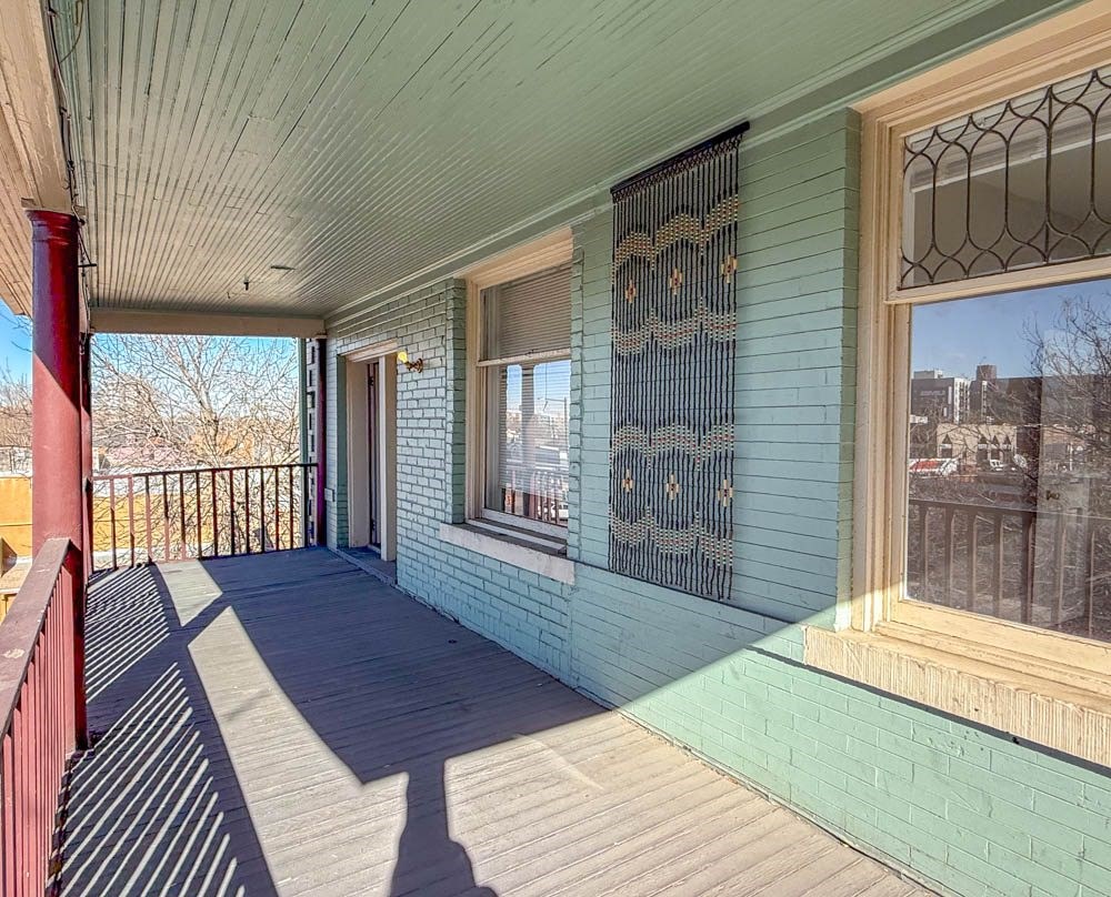 A porch with a red railing and a green wall.