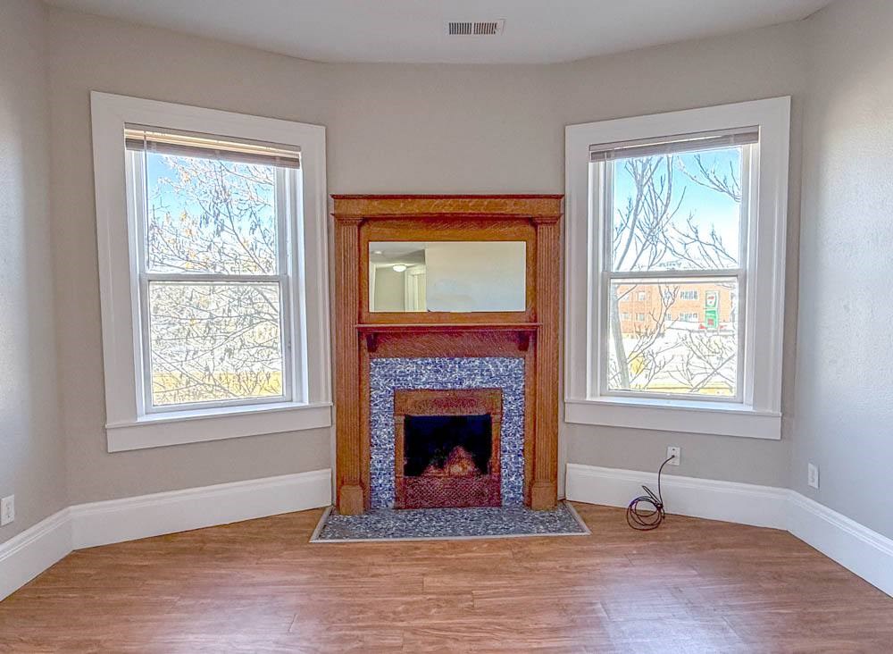 A room with a fireplace and two windows.