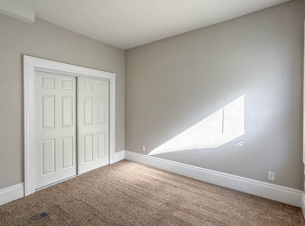 A room with a white door and carpeted floor.