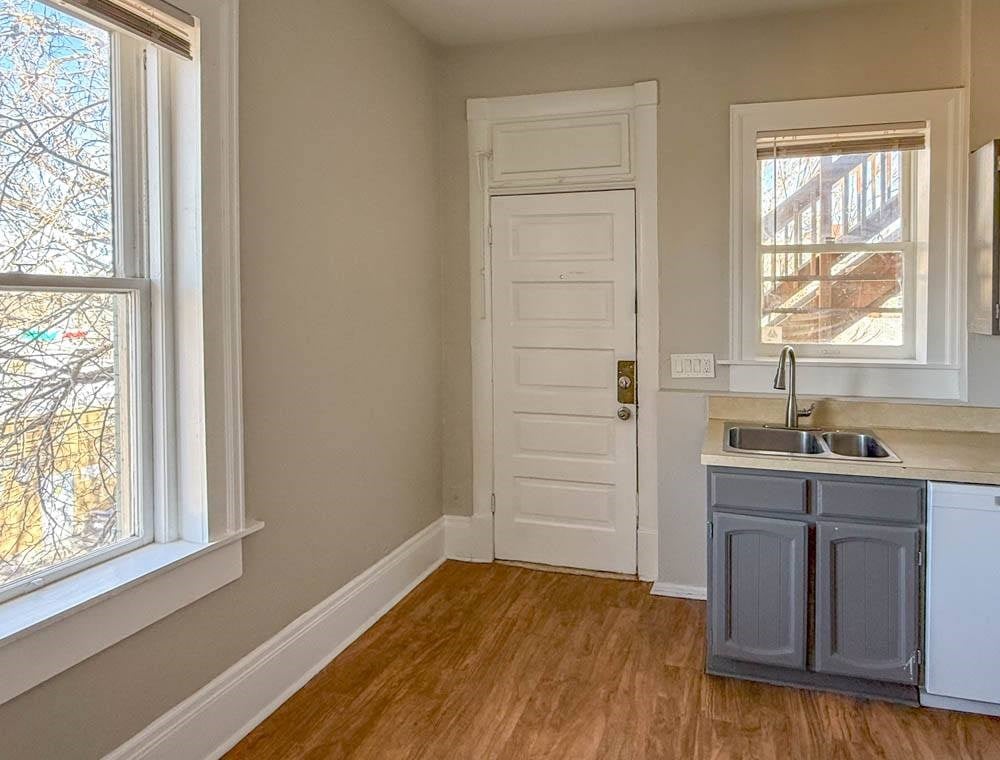 A kitchen with a white door, a window, and a sink.