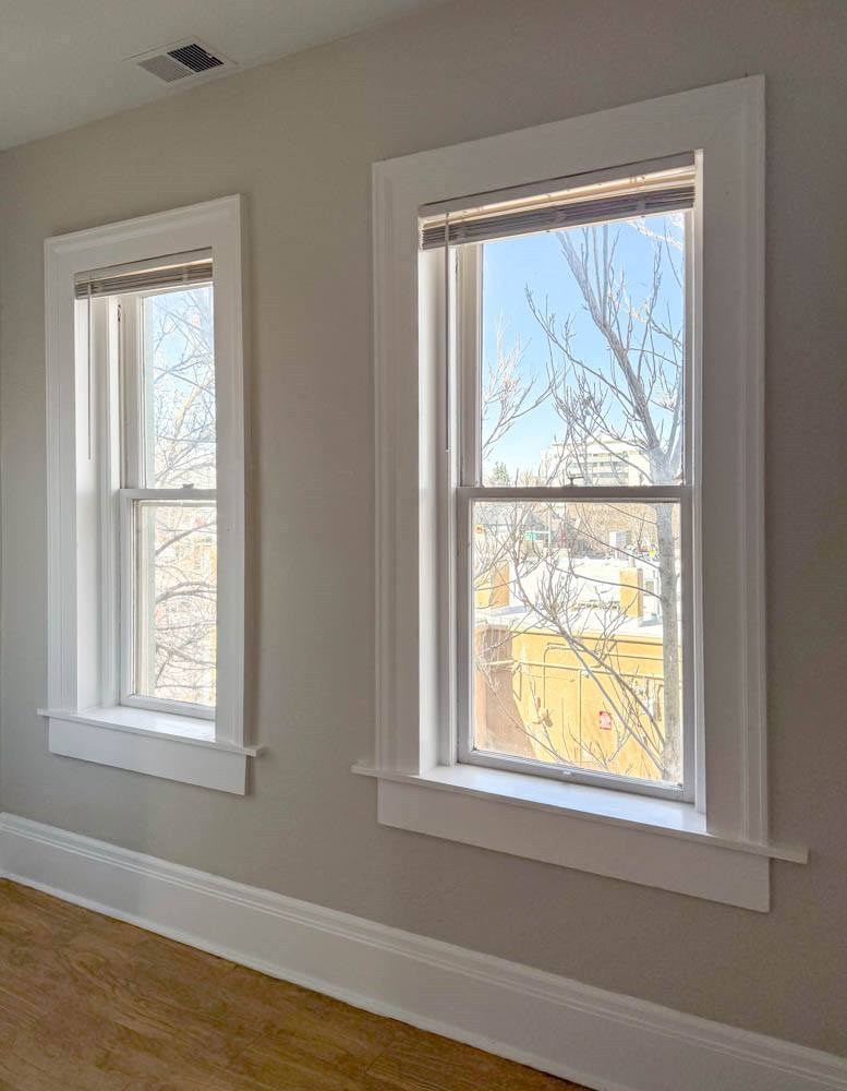 Two windows in a room with white frames.