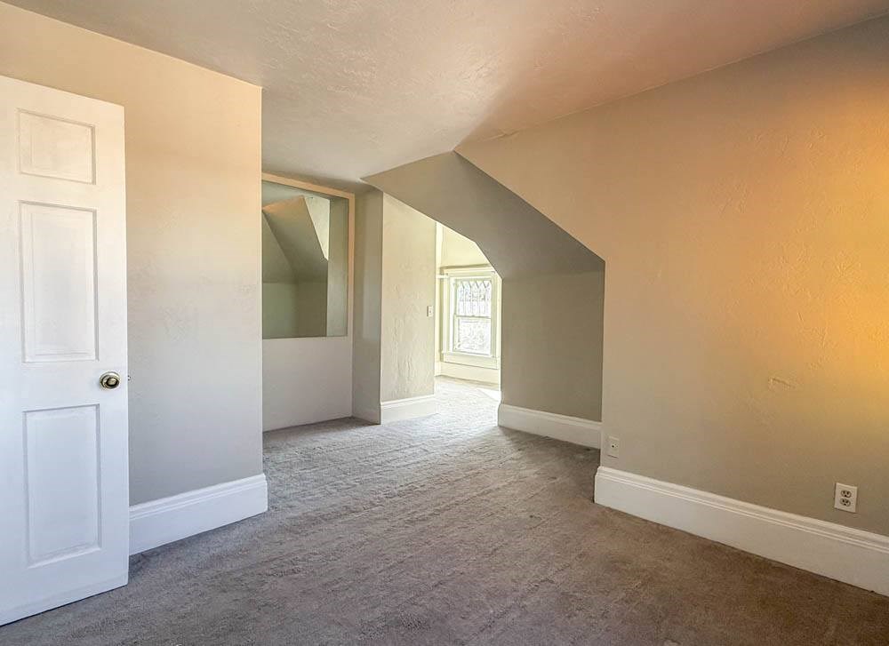 A room with a white door and carpeted floor.