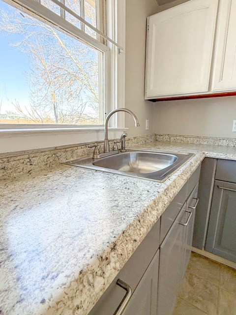A kitchen with a marble countertop and a window.