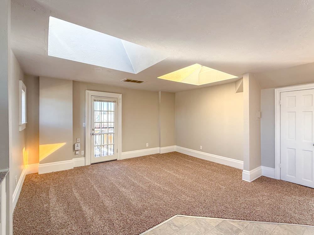 A room with a carpeted floor and a skylight.