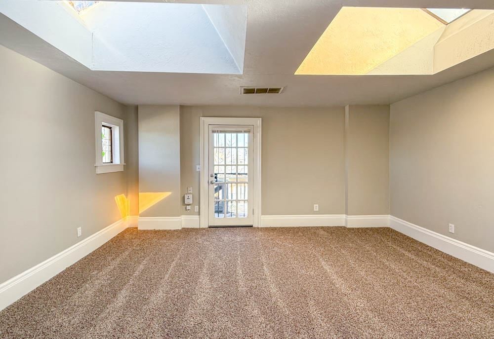 A room with a carpeted floor and a door leading to a balcony.
