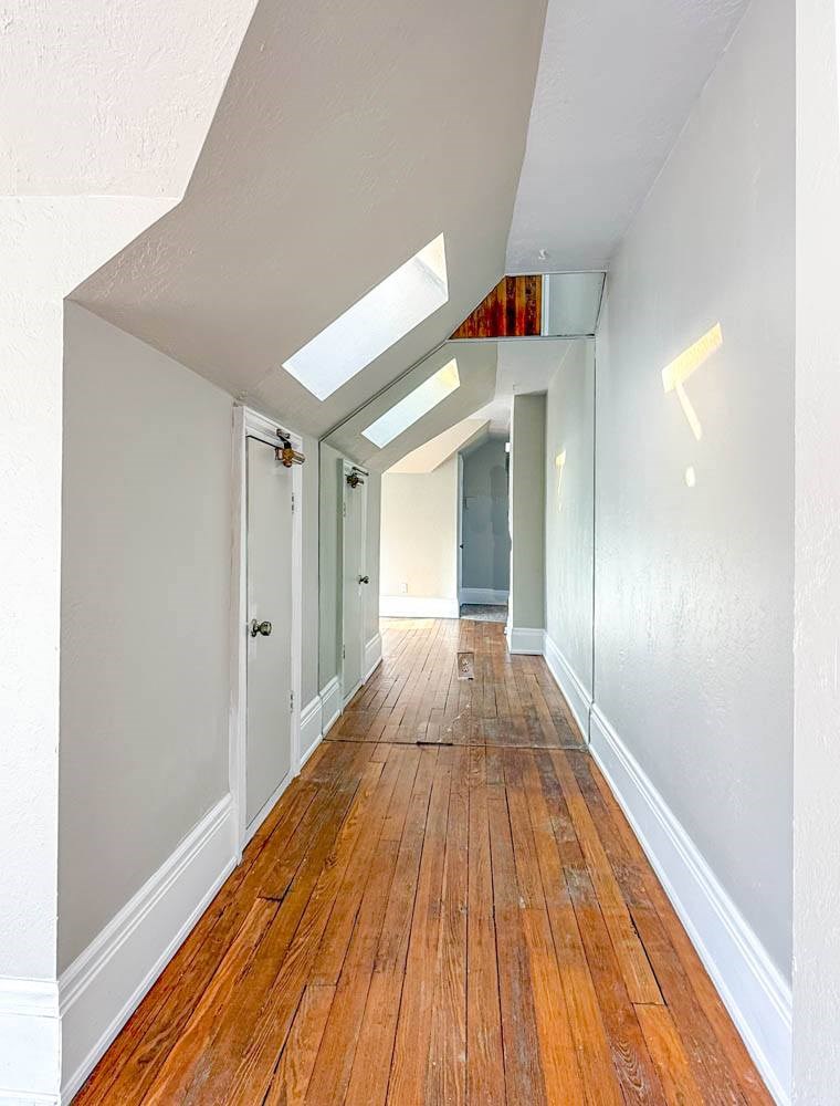 A long hallway with wood floors and white walls.