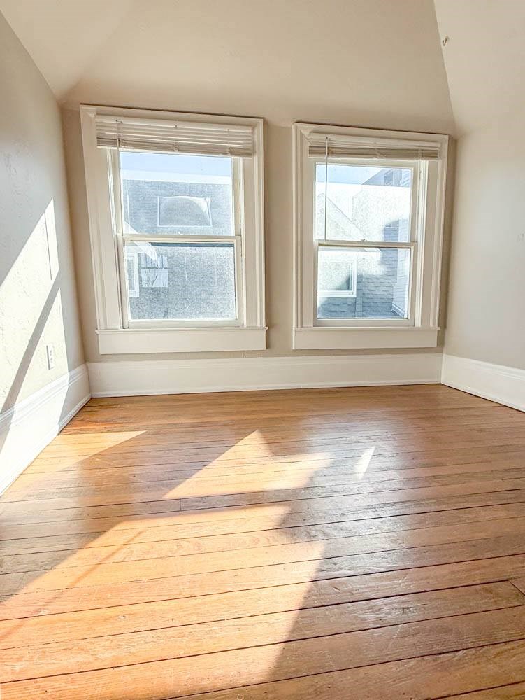 A room with wooden floors and two windows.