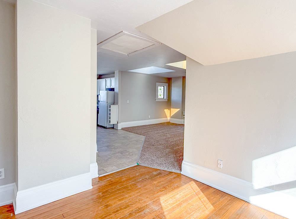 A room with a wooden floor and a rug in the middle.