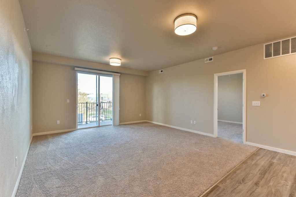 an empty living room with a door to a balcony