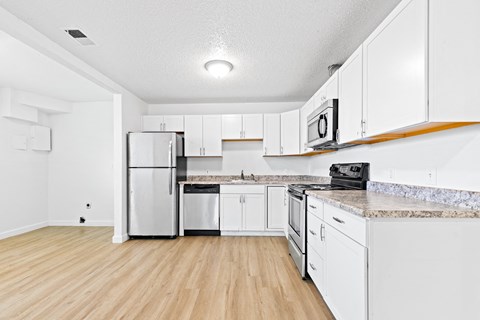 an empty kitchen with white cabinets and stainless steel appliances