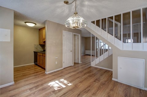 an empty living room with a staircase and a kitchen