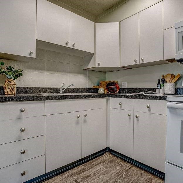 a white kitchen with white cabinets and a sink