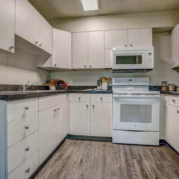 a white kitchen with a stove and a microwave