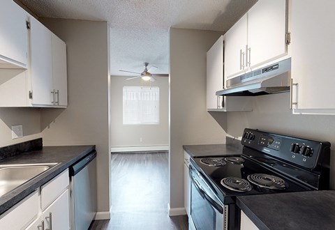A kitchen with a black stove top oven and white cabinets.