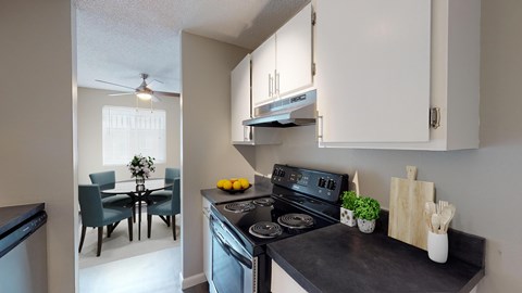 A kitchen with a black countertop and a dining area with a table and chairs.