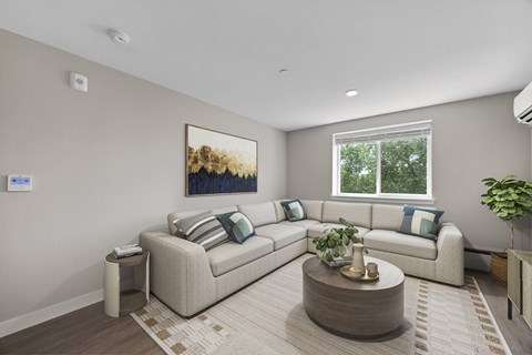 A living room with a large couch, a coffee table, and a painting on the wall.