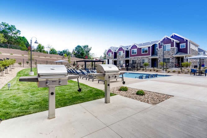 a pool with two bbq pits in front of an apartment building