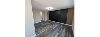 a empty living room with a black wall and wood flooring