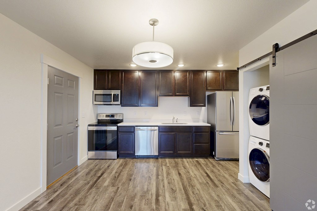 A modern kitchen with dark wood cabinets and stainless steel appliances.