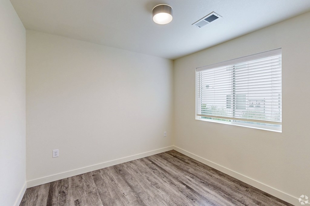 A room with a window and wooden flooring.