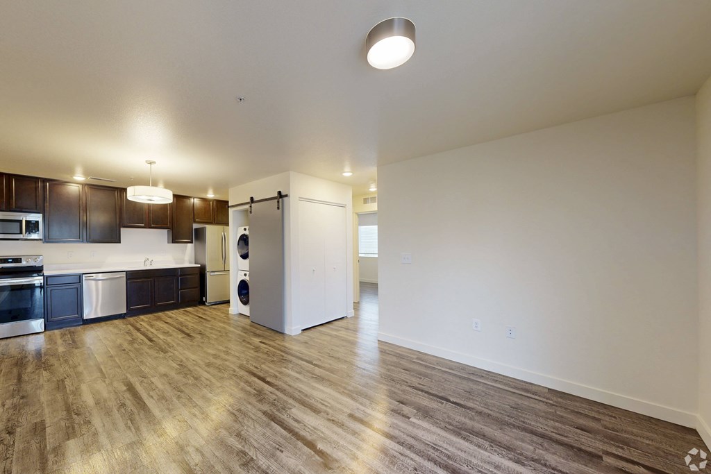 A kitchen with dark wood floors and white walls.