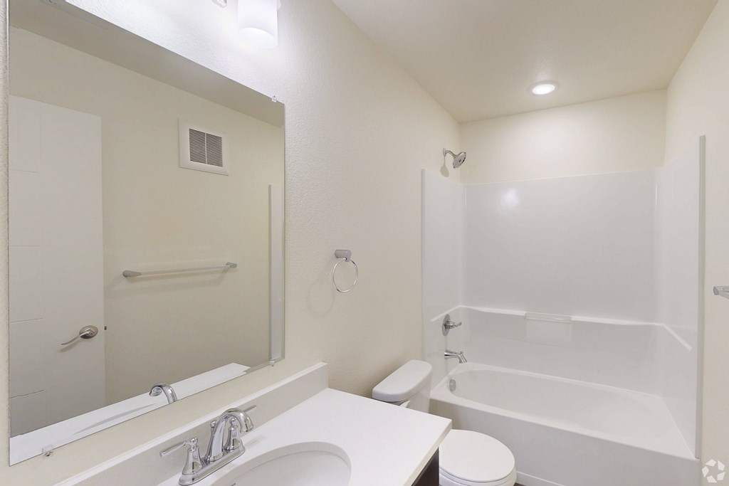 A white bathroom with a toilet, sink, and bathtub.