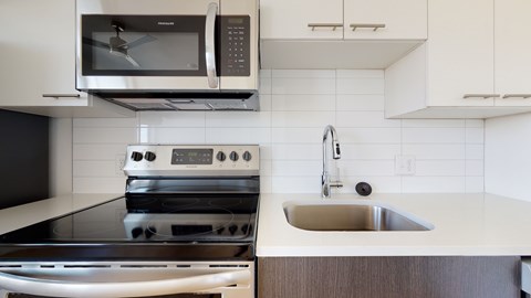 A modern kitchen with a stove, oven, microwave, and sink.