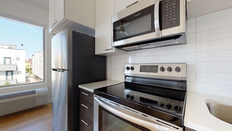 A modern kitchen with a stainless steel refrigerator, oven, and microwave.