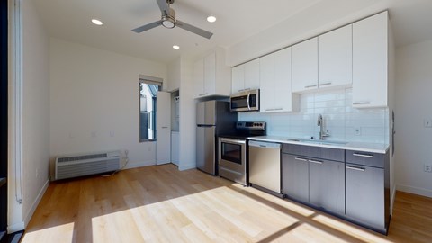 A kitchen with white cabinets and a wooden floor.