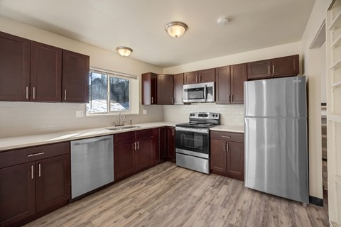 A kitchen with brown cabinets and stainless steel appliances.