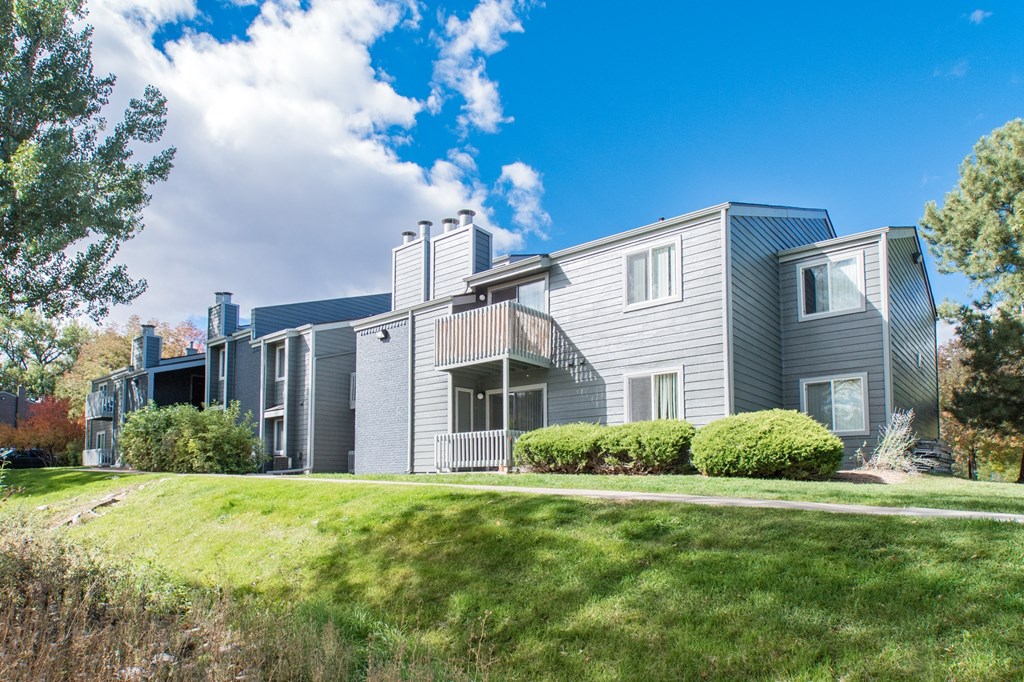 the view of an apartment building with green grass and a blue sky