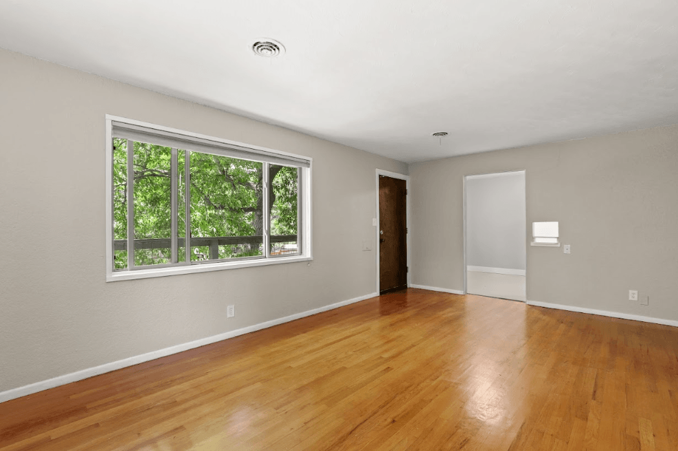 a bedroom with hardwood floors and a large window