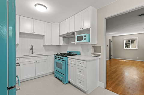 A kitchen with white cabinets and a blue refrigerator.