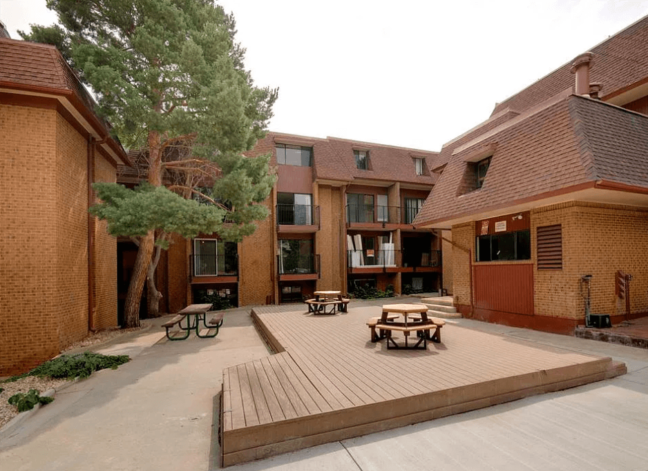 A courtyard with a wooden deck and benches surrounded by brick buildings.