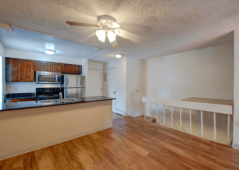 A kitchen with wooden floors and a ceiling fan.